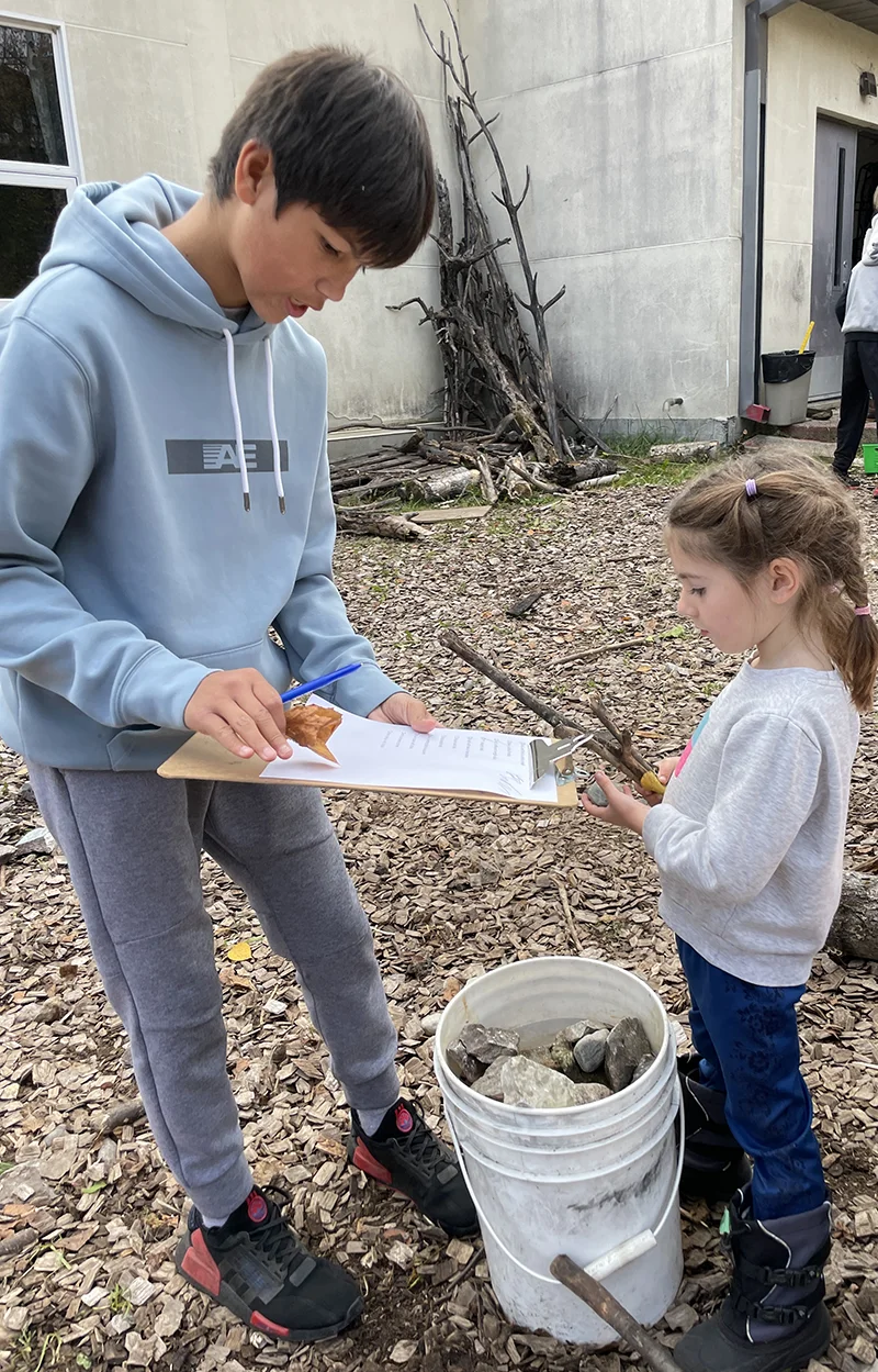 An older and younger student learn together at EcoSchool