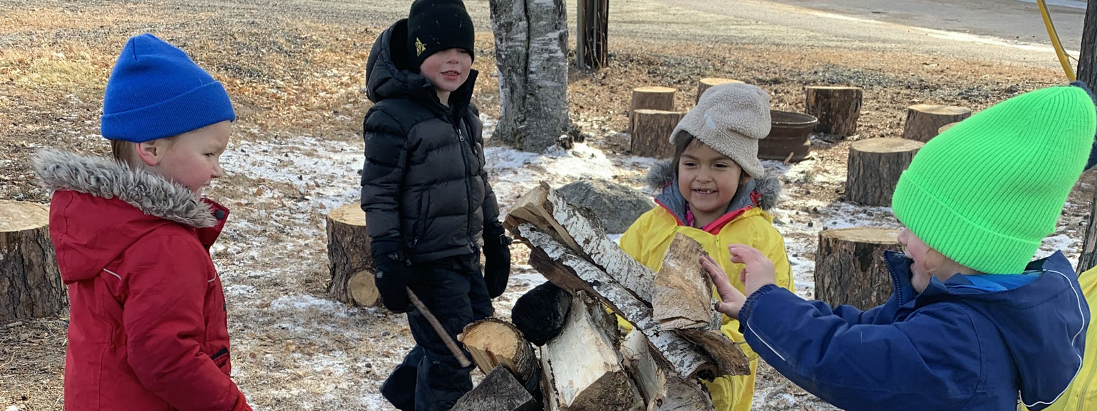 A group of kids helps pile logs for a fire outside Sioux Narrows Public School