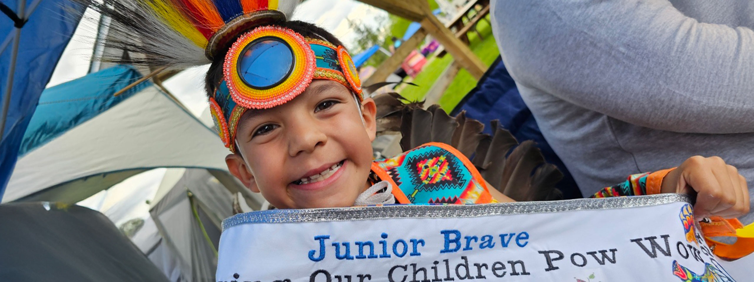 Smiling indigenous boy in powwow regalia