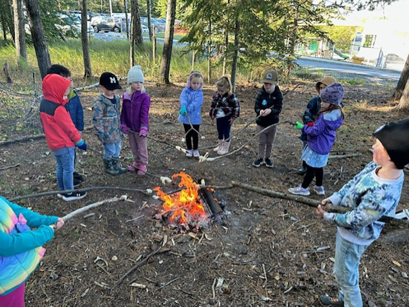 Students roast food over a fire outside the school