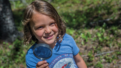 An outdoor learning student shows the camera her magnifying glass.
