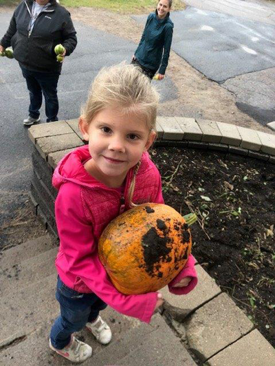 A student shows off her pumpkin from the school garden