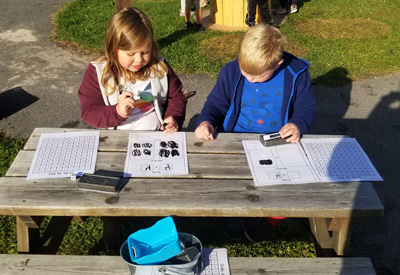Two students sit outside and work on French math worksheets