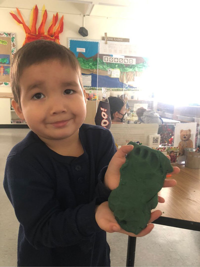 A student shows his STEM creation to the camera, a footprint in clay
